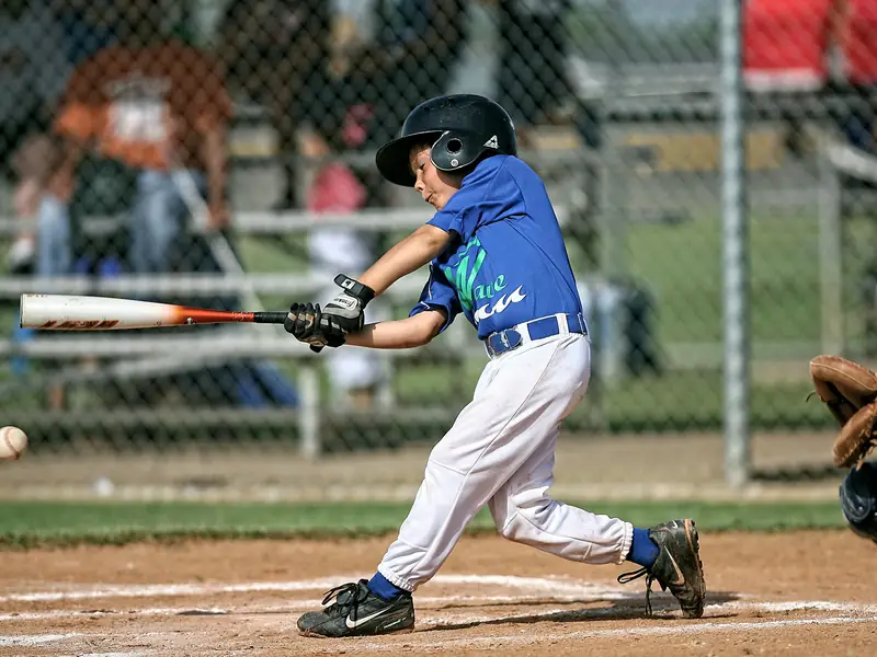 A youth player mid-swing at the plate.