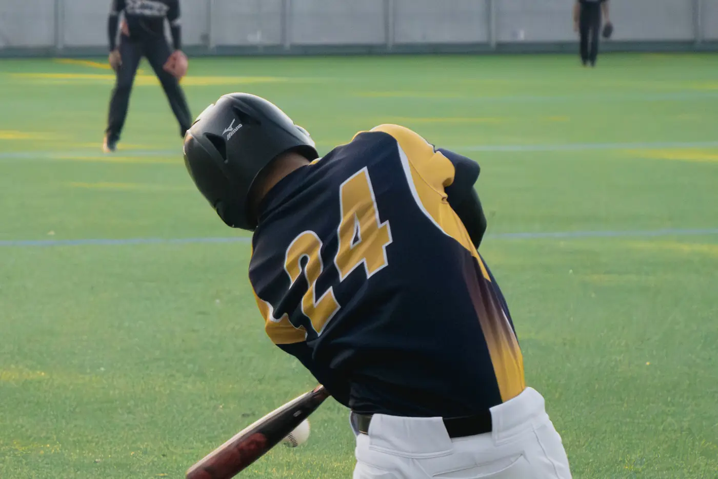 A hitter finishing a swing, seen from behind.